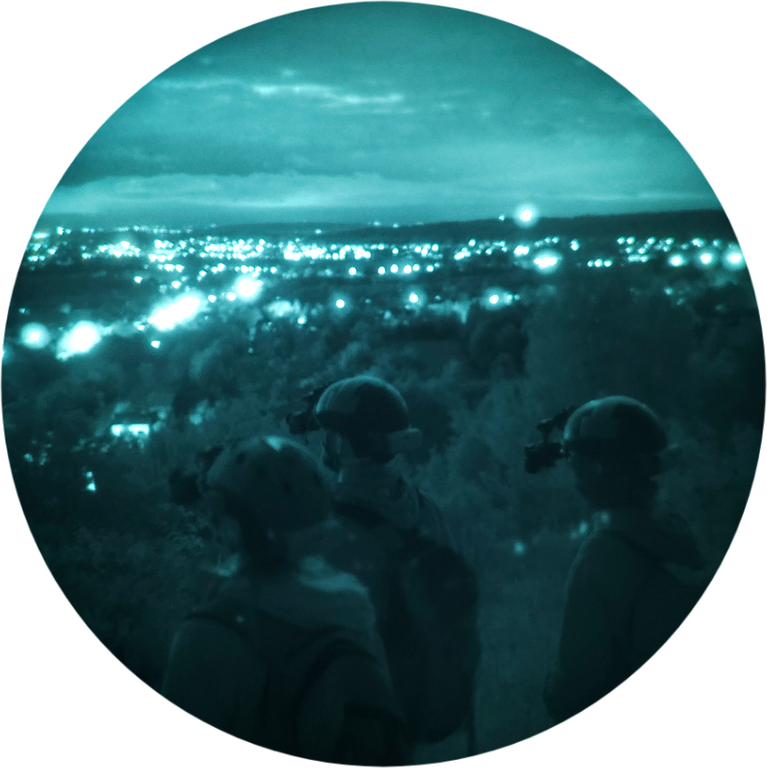 Grupa uczestników nocnej wycieczki obserwująca panoramę miasta przez gogle noktowizyjne